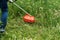 Worker mows the grass with a gasoline string trimmer