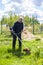 Worker mows grass and weeds with a lawn mower in the country