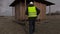 Worker with nails and hammer walking to wooden building