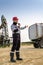 Worker near pumpjack and tank trailer in the oilfield.