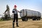 Worker near pumpjack and tank trailer in the oilfield.