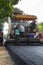 Worker operating industrial asphalt paver machine during highway construction