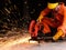 Worker in orange color mechanic jumpsuit using electric wheel grinding on steel