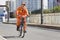 Worker in orange cycles in Beijing downtown, China