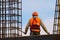 Worker in orange with hammer on scaffolds