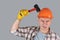 A worker in an orange hardhat hits a helmet with a hammer, protective workwear in industry, copyspace