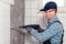 A worker in overalls and protective glasses dismantles facing tiles with a perforator