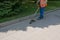 A worker in overalls with a trimer in his hands mows the grass on the lawn and paths in the park. Territory care