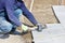 A worker places granite blocks on the sidewalk with a rubber hammer on a marked area