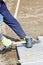 A worker places granite tiles on the sidewalk, leveling them with a rubber mallet. Vertical image