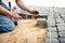 Worker placing stone tiles in sand for pavement, terrace. Worker placing granite cobblestone pavement at local terrace