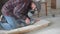 Worker in a plaid shirt and respirator cuts ceramic tiles with an angle grinder