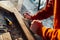 A worker planes a wooden bar with a plane