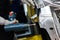 Worker prepares to screw car body parts on workshop conveyor