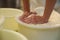 Worker pressing curd into mould at cheese factory