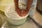 Worker pressing curd into mould at cheese factory