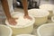 Worker pressing curd into mould at cheese factory, closeup