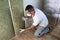 Worker in protective goggles and respirator insulating rock wool insulation in wooden frame for future house walls for cold