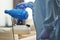 Worker in protective suit holding disinfectant and standing indoors