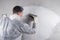 A worker in a protective uniform puts the finishing putty on a concrete wall