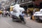 Worker pulling bale on tricycle rickshaw along a busy street in Kolkata