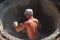 Worker punching a hole with a perforator for a pipe in a reinforced concrete well