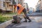 Worker pushes a manual roller for asphalt paving of the sidewalk.. Road works close-up