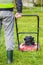 Worker pushing lawnmower in garden