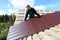 Worker puts the metal tiles on the roof