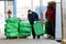 Worker puts on pallets loaded with green bags.