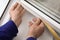 Worker putting rubber draught strip onto window indoors, closeup