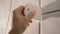 Worker putting tiles on the wall in the bathroom. His hands are placing the tile on the adhesive.