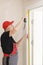 Worker in red cap and work suit with the measuring tape. Man is installing the doors. Measure tape in hands. Repair works.