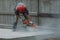 Worker in a red helmet is sawing concrete with a large grinder