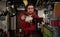 Worker in red uniform operating in manual lathe in metal big workshop