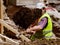 Worker with reflective vest shoveling clay