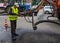 Worker repairing the hole in the asphalt on a city street using liquid asphalt supply hose through special machines