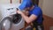 Worker repairing washing machine in laundry room