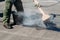 Worker repairs the roof with molten tar from a bucket with a broom