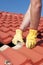 Worker replacing roof tiles on house