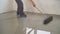 A worker rolls out the liquid floor with a trowel. Squeegee for distributing the mixture. The worker levels the liquid