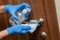 Worker`s hand in a rubber protective glove with a rag wiping the doorknob. Disinfection of premises