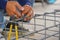 Worker`s hand tying reinforcing steel bars, tightening wire on rebar for formwork construction