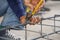 Worker`s hand tying reinforcing steel bars, tightening wire on rebar using a pincers for formwork construction