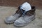 Worker`s shoes dirty from all-day work construction dust on leather boots on concrete with mask protecting lungs from dust