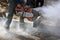 A worker saws concrete with a circular saw, cuts a large curb.