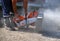 A worker saws a concrete curb with a circular saw.