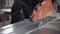 A worker saws off part of the board on a machine with an electric saw. Close-up.