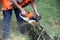 A worker saws a tree branch with a chainsaw.