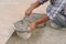 Worker scooping mixed mortar in a bucket to tiled on the floor